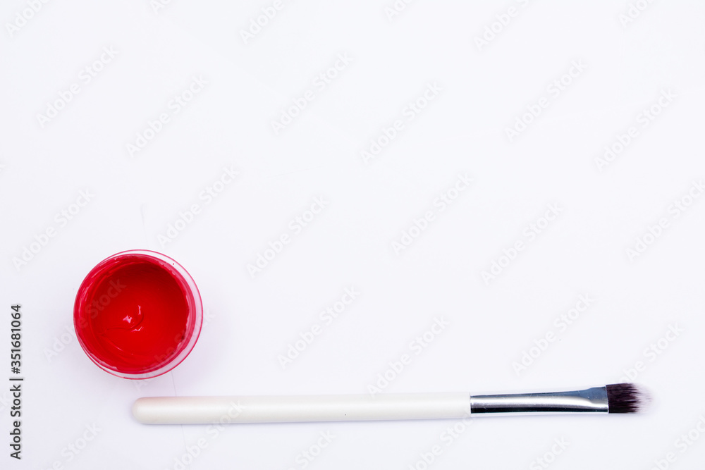 Jar of gouache with red paint and an artist's brush, a white background, copy space Jar of gouache with red paint and an artist's brush, a white background, copy space
