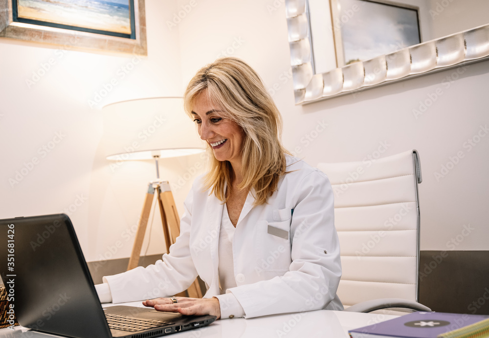 Cheerful doctor using laptop in office Cheerful doctor using laptop in office