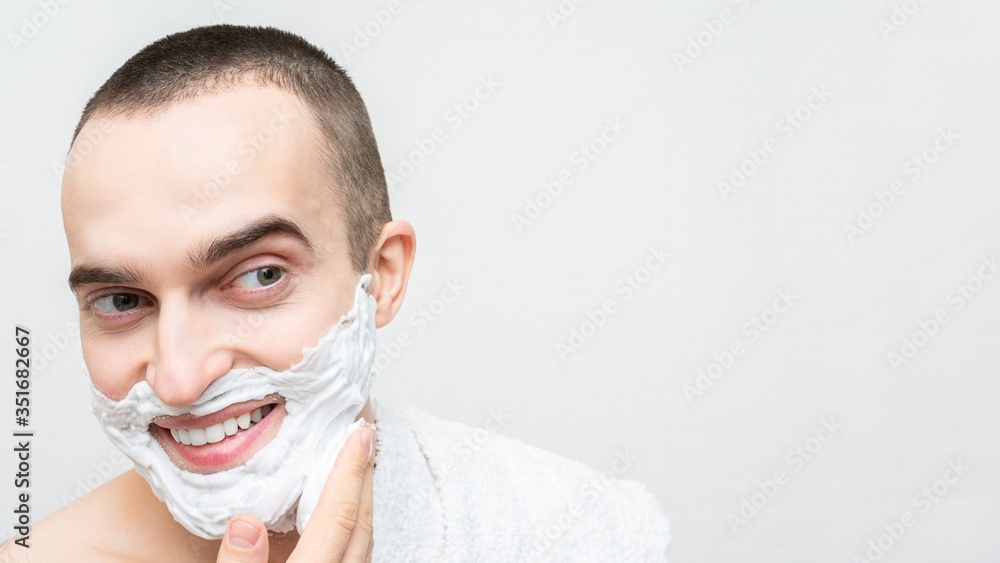 Cheerful guy with shaving foam on his face, white background, 16:9, copy space