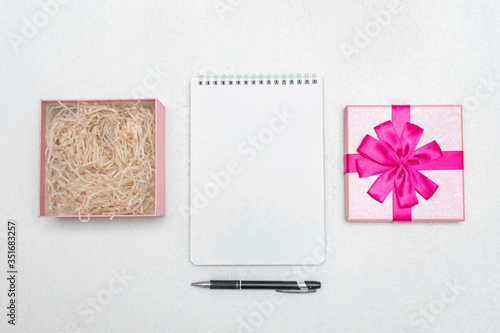 Notebook, open gift box with pink ribbon and pen, copy space, top view