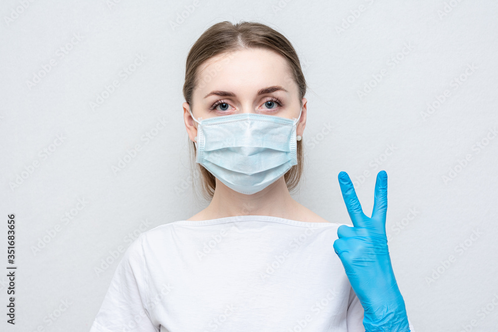 Nurse in medical mask and gloves show sign two, portrait, close up Nurse in medical mask and gloves show sign two, portrait, close up