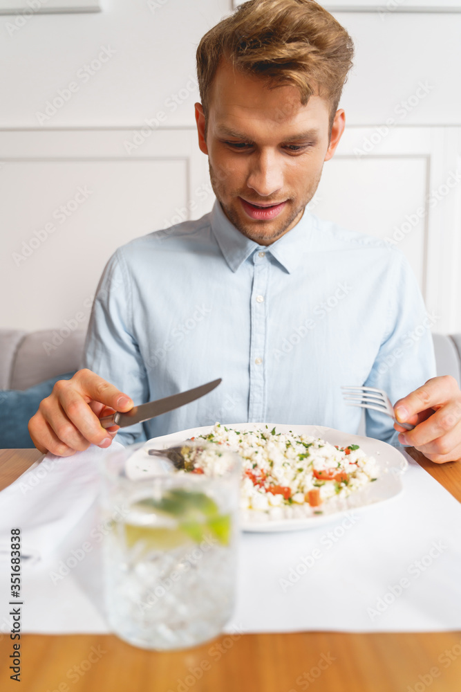 Handsome young man eating delicious vegetarian food in cafe Handsome young man eating delicious vegetarian food in cafe