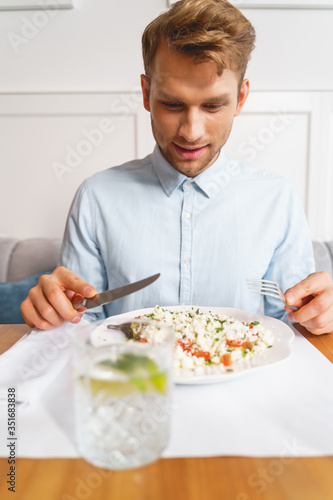 Handsome young man eating delicious vegetarian food in cafe