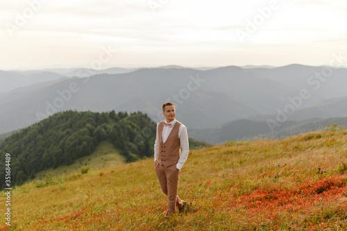 The groom is walking alone on the background of autumn mountains.