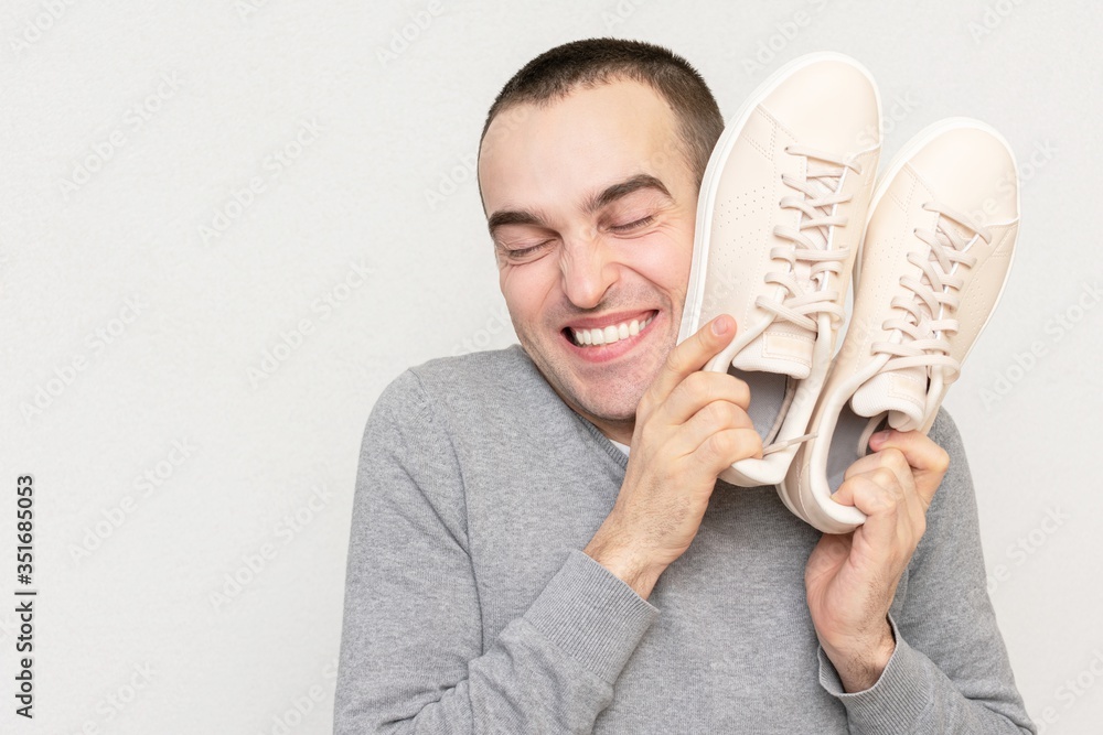 Cheerful man likes to play sports, man shows off with his sneakers, portrait, close-up Cheerful man likes to play sports, man shows off with his sneakers, portrait, close-up