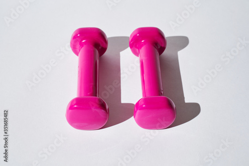 Pink dumbbells for fitness on a white background.