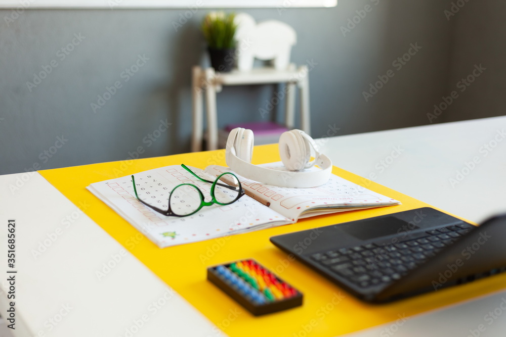 laptop, glasses, headphones, a notebook lie on the desk, desk of a modern schoolboy, concept of online school, education on the Internet