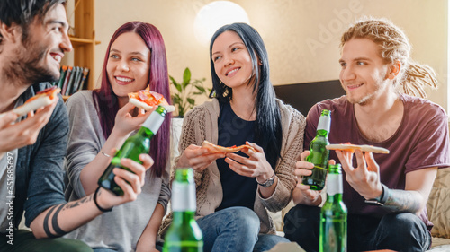 Youth having fun drinking beer with pizza and roaring in the house. Friends and togetherness lifestyle concept.