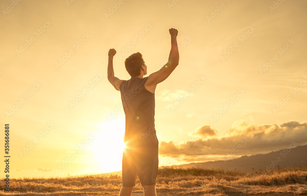 Young man flexing his arms on a mountain top. People feeling strong and confident, and never giving up concept. 
