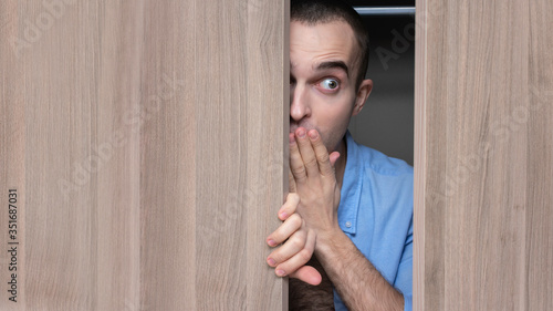 Wallpaper Mural Lover hiding in the closet with clothing, afraid of being found, portrait, close up, copy space, 16:9 Torontodigital.ca