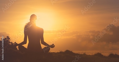 silhouette of a woman doing yoga meditating at sunset. 