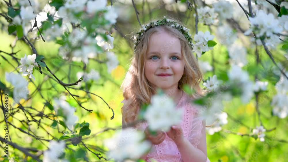 Portrait of a little cute girl in a flowered garden. A girl with white hair in a beautiful dress near the blooming branches of an apple tree. children, emotions. Portrait of a little cute girl in a flowered garden. A girl with white hair in a beautiful dress near the blooming branches of an apple tree. children, emotions.