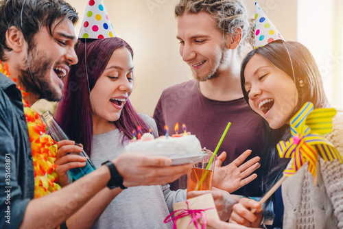 Close up photo of happy young girl celebrating birthday among friends while standing in room at home