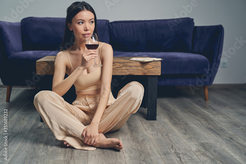 Beautiful young woman drinking red wine at home