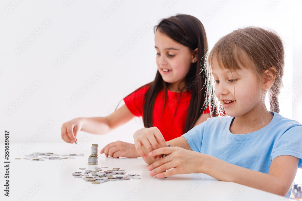 portrait of little girls sitting at table and calculating money portrait of little girls sitting at table and calculating money