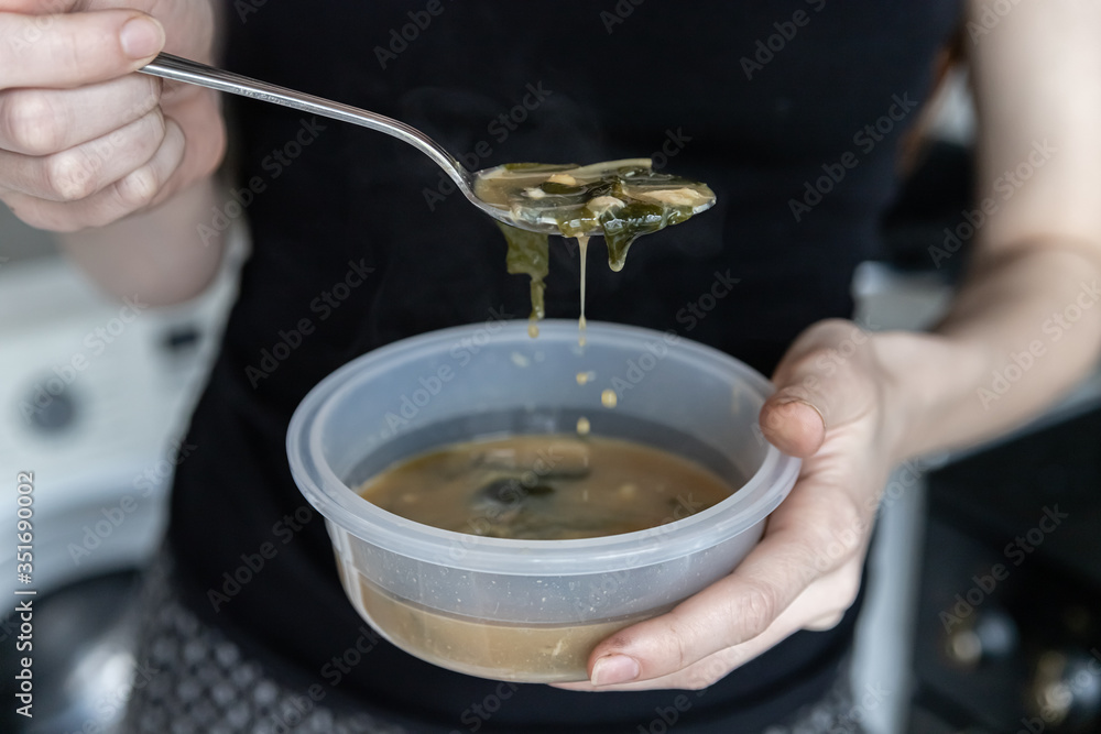 Soft focus. Girl eats miso soup from a plastic container. Quick hot food Soft focus. Girl eats miso soup from a plastic container. Quick hot food