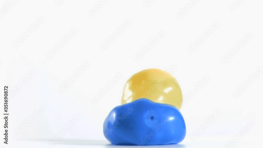 Yellow balloon rebounding in super slow motion on a blue one Yellow balloon rebounding in super slow motion on a blue one