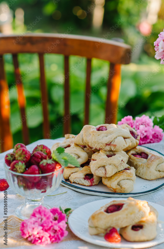 Sweet buns on a table with strawberries. Rustic style photo in nature. Sweet buns on a table with strawberries. Rustic style photo in nature.