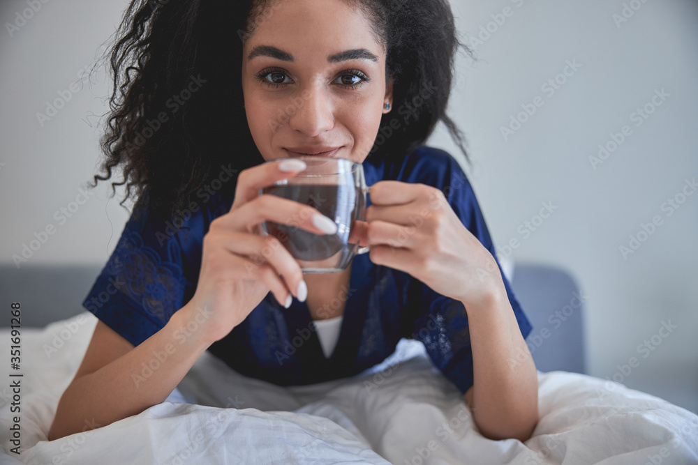 Positive delighted young woman enjoying her aroma coffee