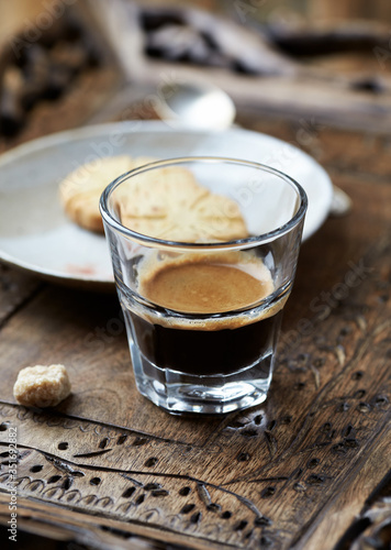 Coffee in glass cup on rustic wooden background. Close up.