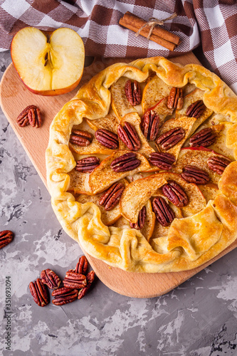 crispy apple galette with pecans on a rustic wooden background
