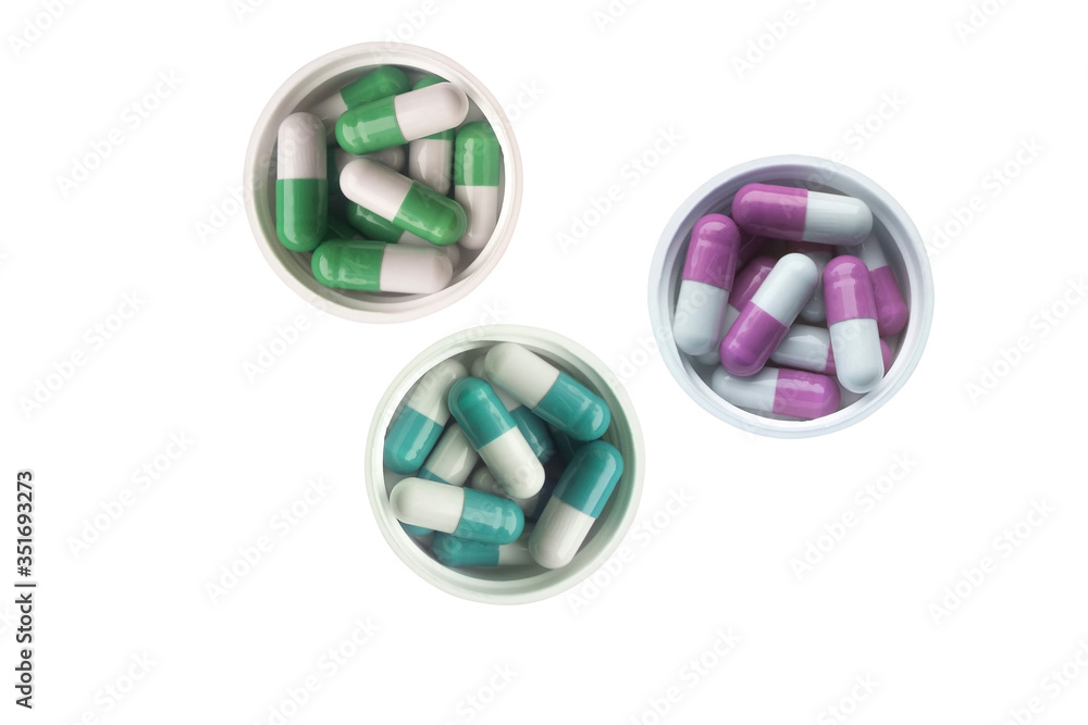 Three round plastic caps are filled with colorful capsules. Capsules on a white background top view. Three round plastic caps are filled with colorful capsules. Capsules on a white background top view.