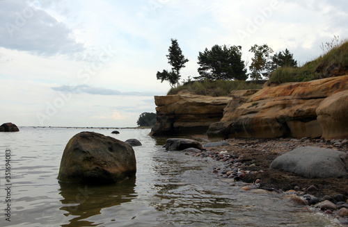 Scenic cliff with sundstone layers. the boulders on shore of Baltic sea. Summer storm time.