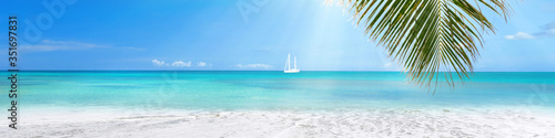Sunny tropical Caribbean beach with turquoise water background, sail boat in lagoon