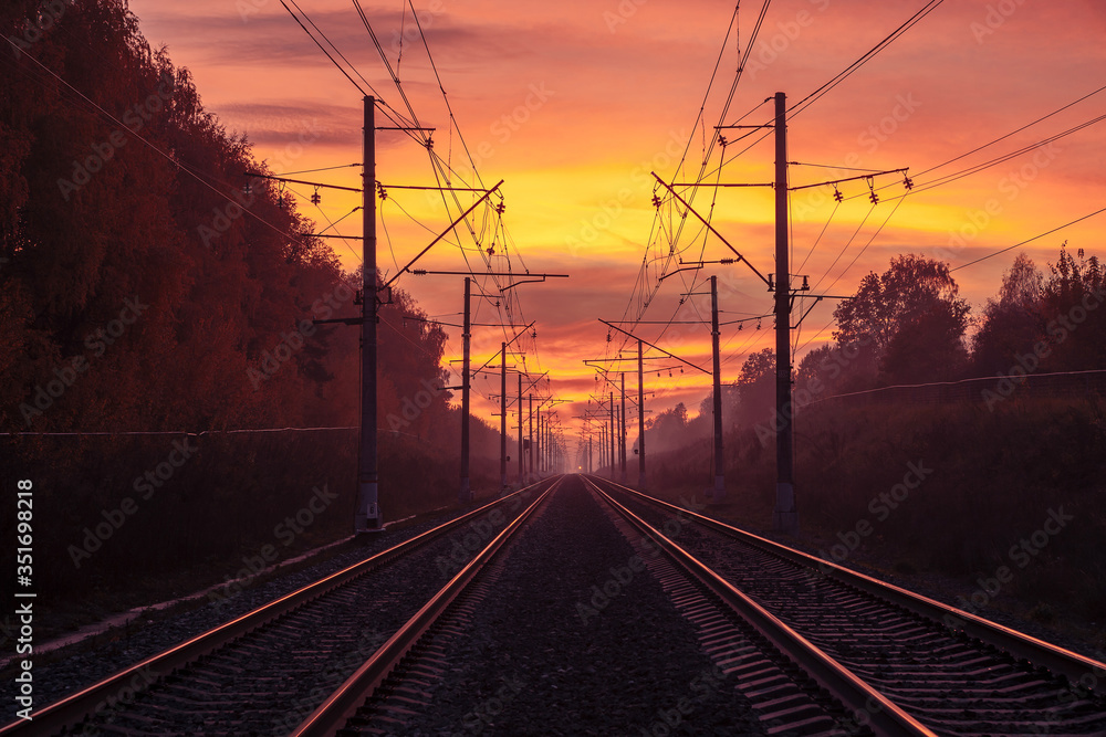 Rails extending into the distance, illuminated by the sunset sky.