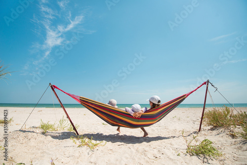 Children have a rest in a hammock on a sandy seashore