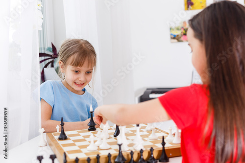 Two cute children playing chess at home