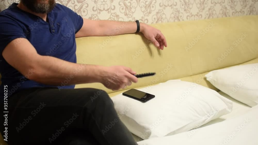 A man switches channels with a remote control from the TV. A man switches channels with a remote control from the TV.
