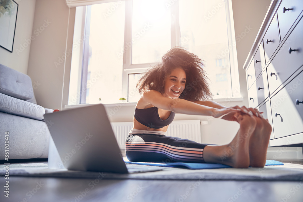Happy curly haired girl doing stretching exercises Happy curly haired girl doing stretching exercises