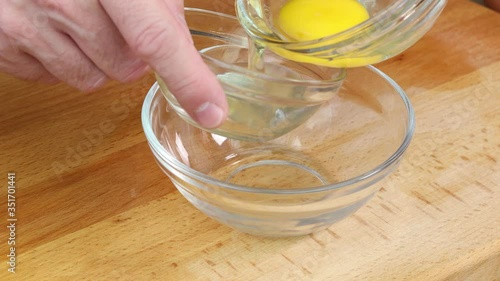 close-up of separating egg yolk from egg white using glass bowls