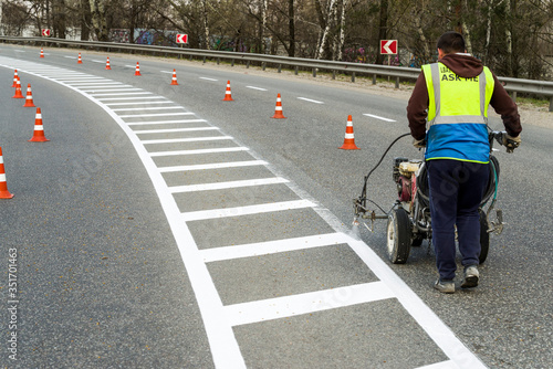 Automated painting by airbrushing of a road using spraying for driving direction, road repair marking on asphalt pavement