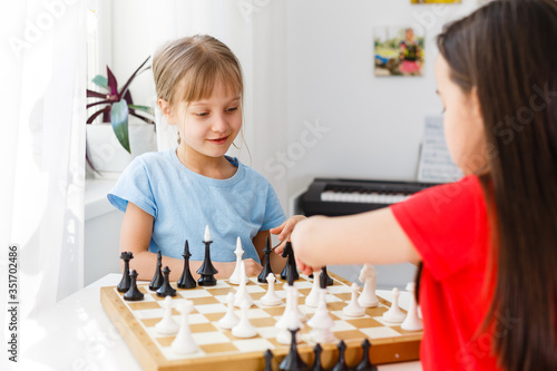 Two cute children playing chess at home