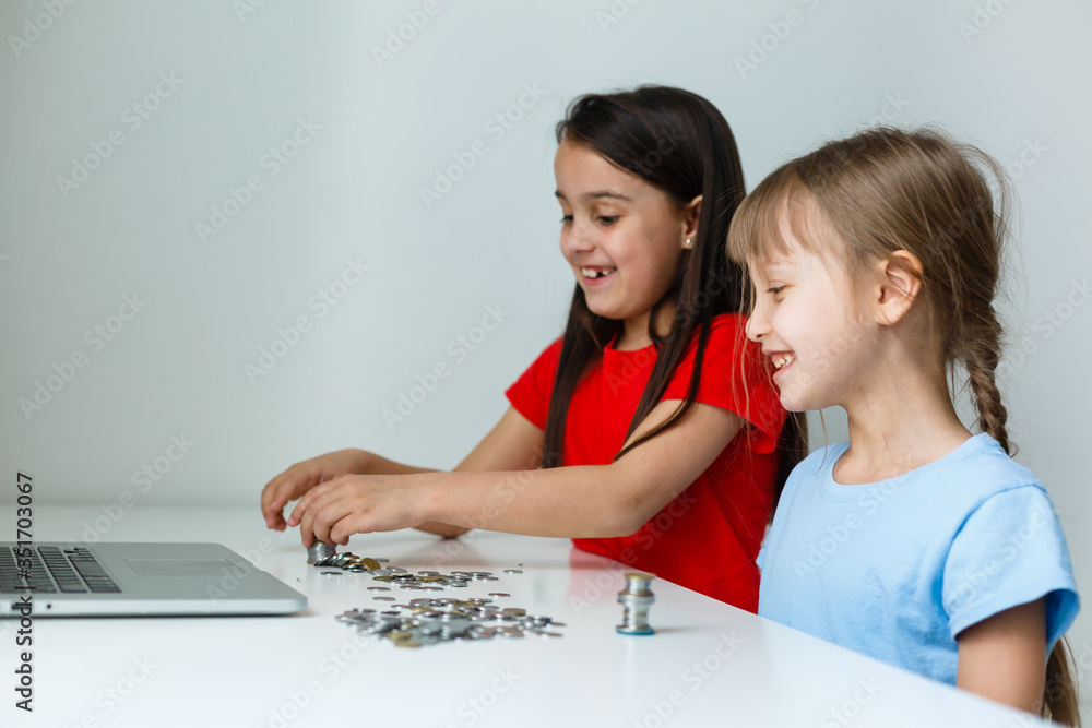 portrait of little girls sitting at table and calculating money