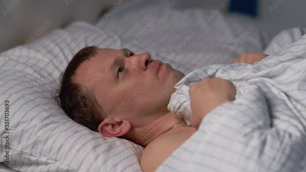 Young man thinks before going to bed lying in bed, suffers from insomnia Young man thinks before going to bed lying in bed, suffers from insomnia