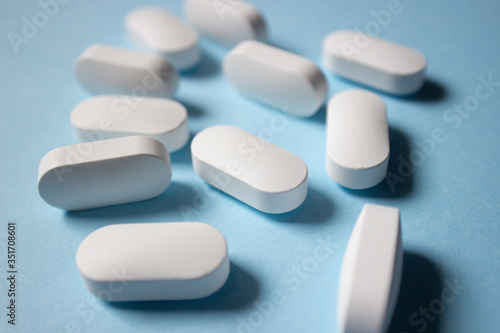Close up of white medical pills on a blue background.