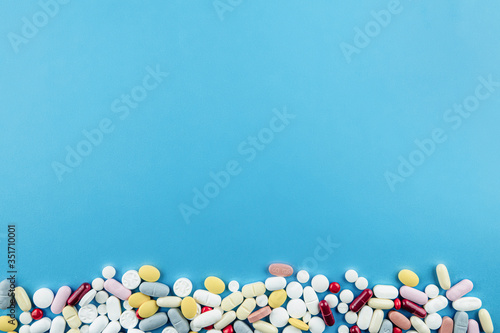 Assorted pharmaceutical medicine pills isolated with blue backgorund. Concept photo on theme Coronavirus and Covid-19.