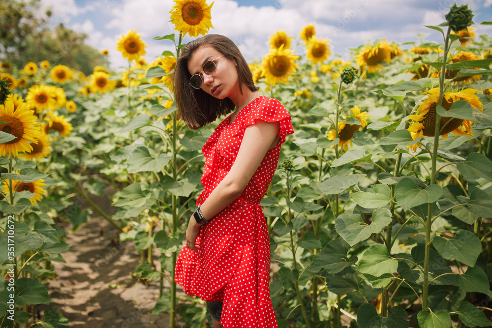 young beautiful caucasian girl in red dress in white dots stay in sunflower field young beautiful caucasian girl in red dress in white dots stay in sunflower field