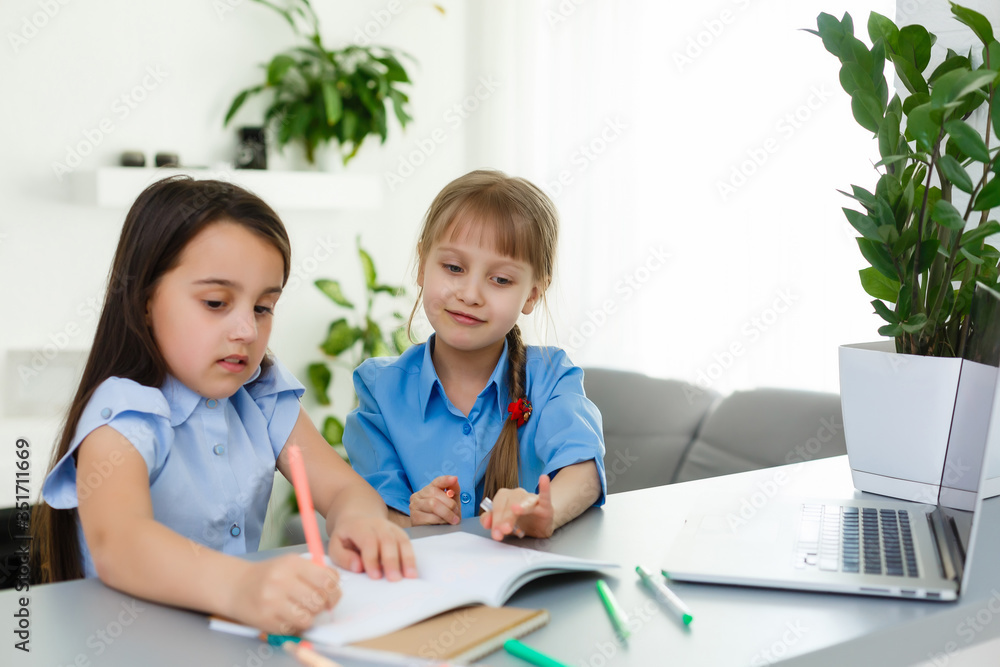 Cool online school. Kids studying online at home using a laptop. Cheerful young little girls using laptop computer studying through online e-learning system. Distance or remote learning Cool online school. Kids studying online at home using a laptop. Cheerful young little girls using laptop computer studying through online e-learning system. Distance or remote learning