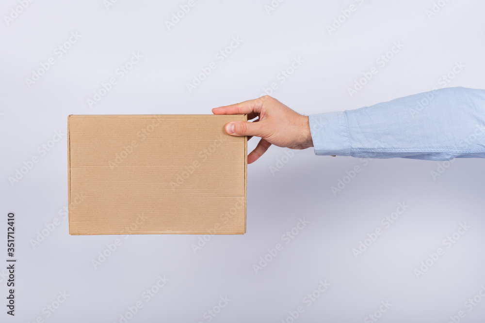 Man holding box at arm's length. Cardboard box. Delivery of parcels. Side view. Man holding box at arm's length. Cardboard box. Delivery of parcels. Side view.
