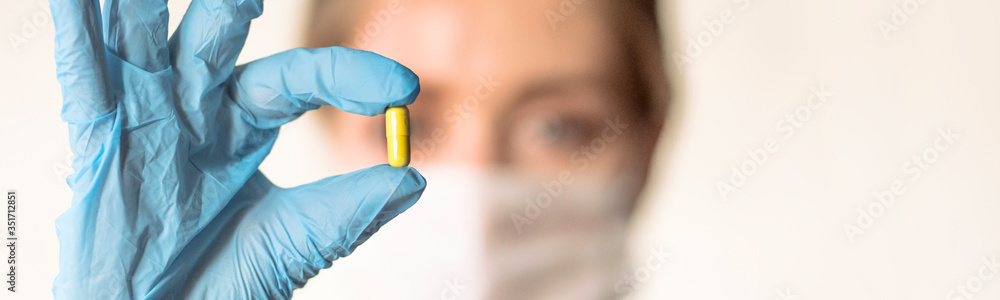 Doctor holding a pill, looking at it and giving it as a treatment to the patient Doctor holding a pill, looking at it and giving it as a treatment to the patient