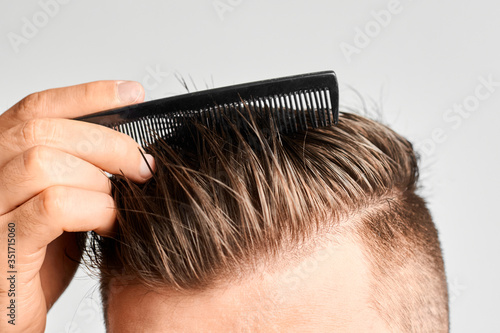 Man combing his clean hair with plastic comb. Hair styling at home. Concept of hair loss or or dandruff