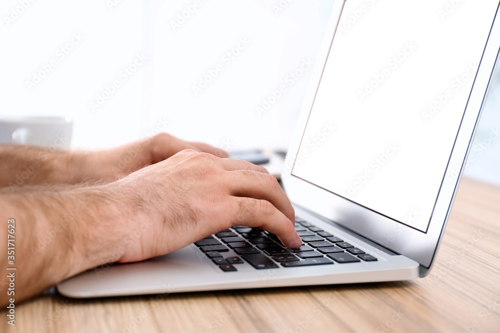 Man working with modern laptop at wooden table indoors, closeup Man working with modern laptop at wooden table indoors, closeup