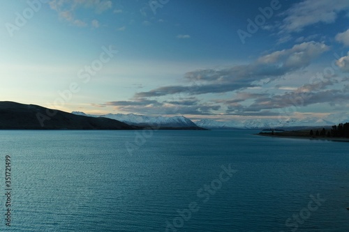 Aerial photograph over vast blue lake with mountains in the distance. South Island, New Zealand. © VisiondeJour