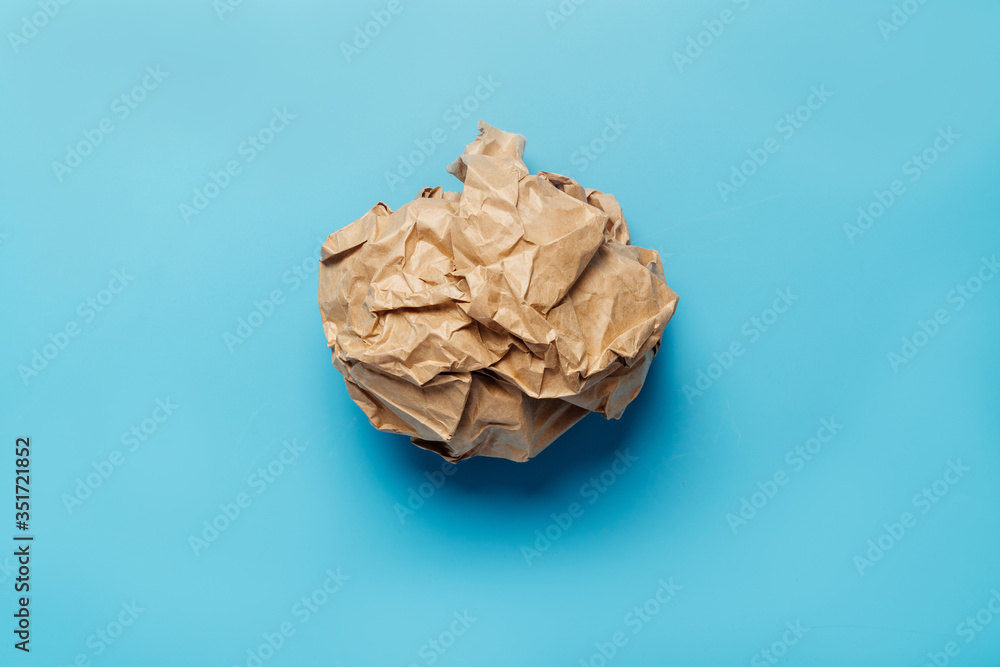 Crumpled brown paper on a blue background. The concept of recycling and recycling, an environmental issue. Crumpled brown paper on a blue background. The concept of recycling and recycling, an environmental issue.