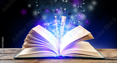 Foto Symphony shining with musical notes from open book on wooden table