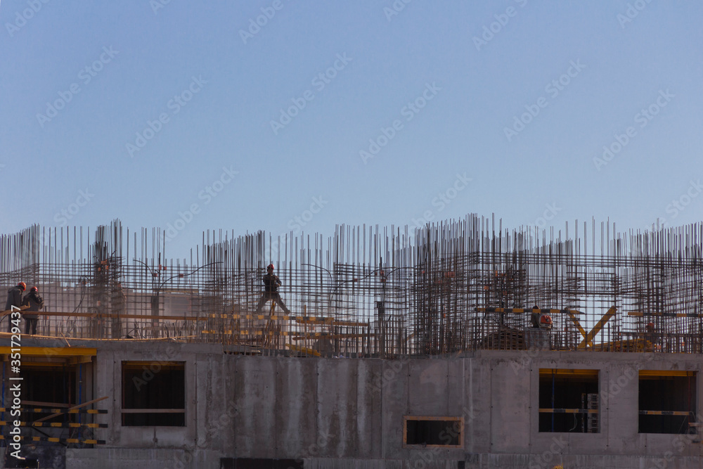 Industrial workers and builders with hardhat in uniform pour concrete and mount reinforcesment carcass at construction site Industrial workers and builders with hardhat in uniform pour concrete and mount reinforcesment carcass at construction site